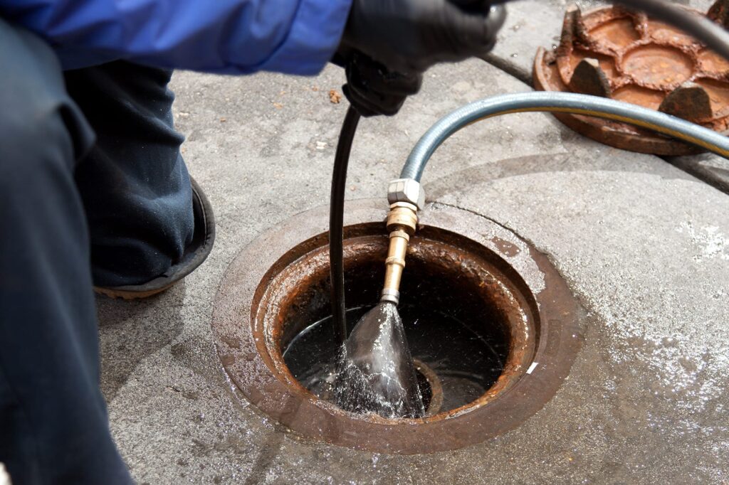 Plumber hydro jetting a sewer line through a manhole in Pottstown